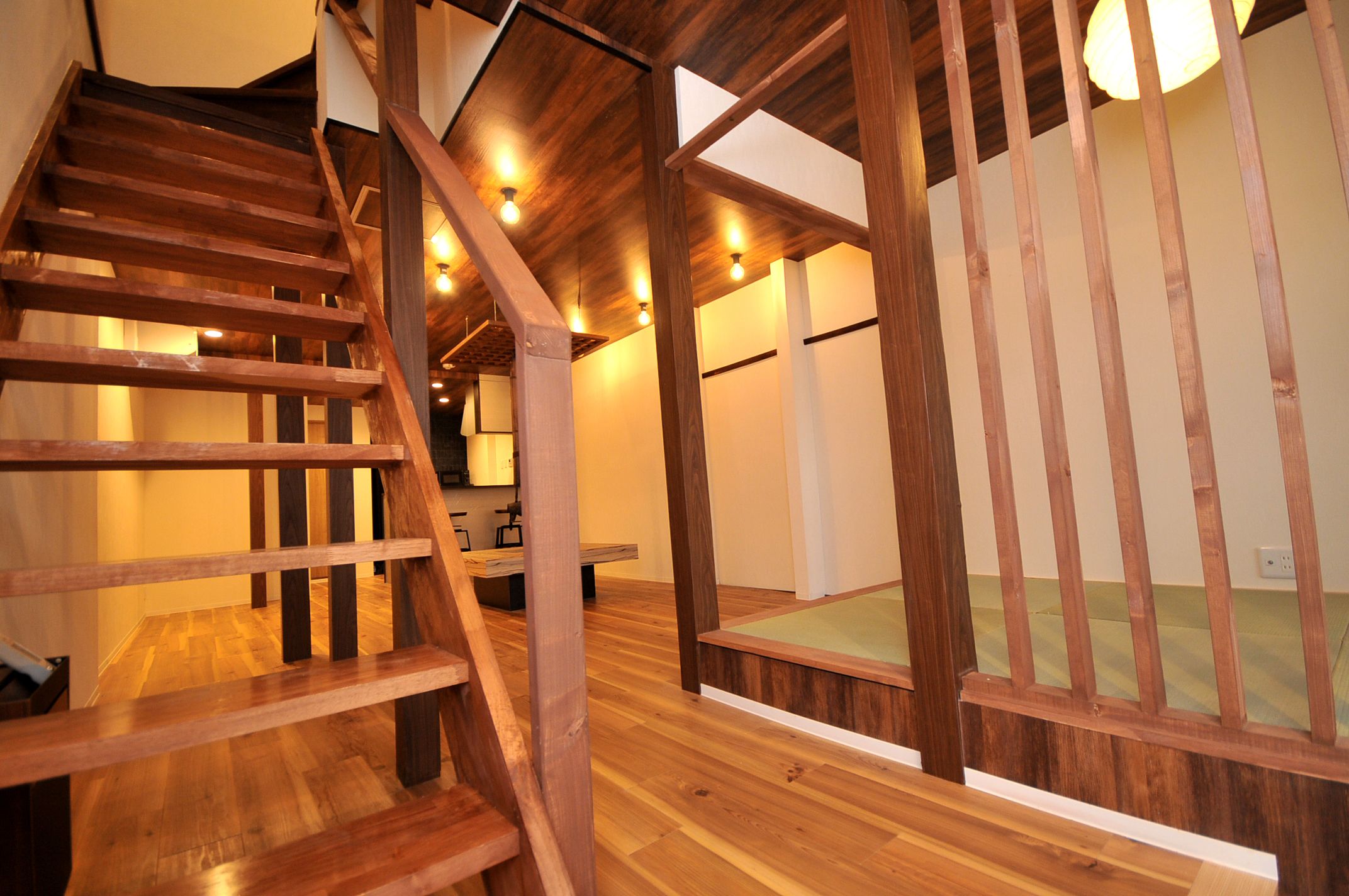 Un escalier en bois avec une rampe en bois, un plancher en bois et un plafond doté d’un éclairage encastré.