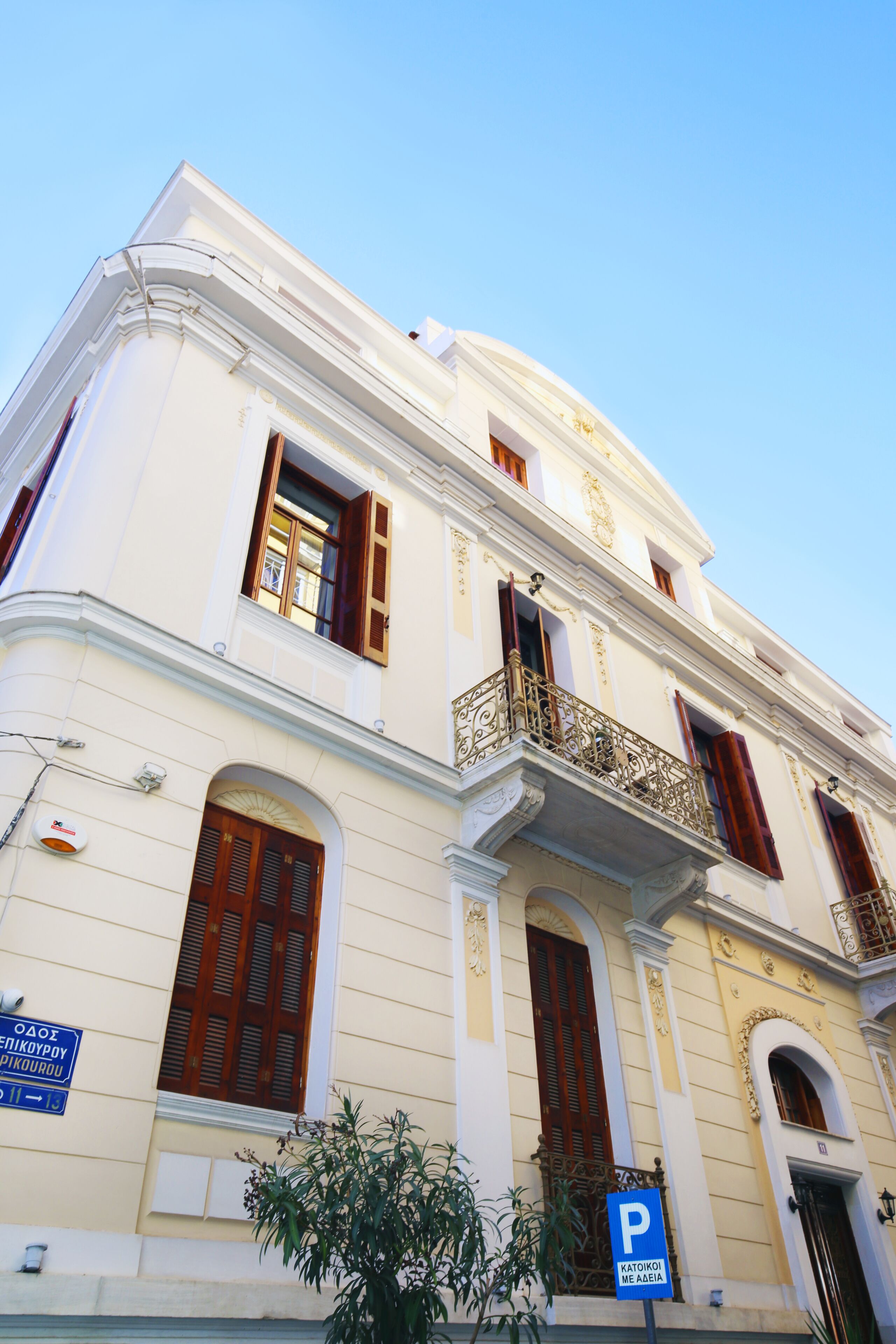A historic building with classical architecture, featuring arched windows and a balcony with ornate railings.