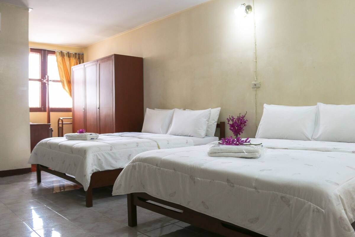 A hotel room with two beds, a wardrobe, and a window with curtains.