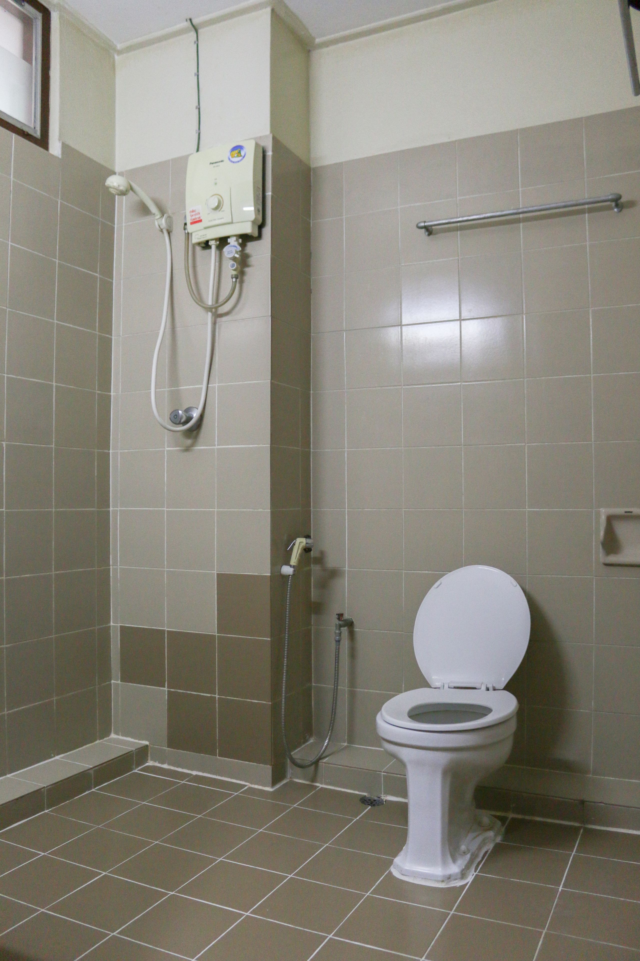 A bathroom with a toilet, a shower, and a hand dryer.
