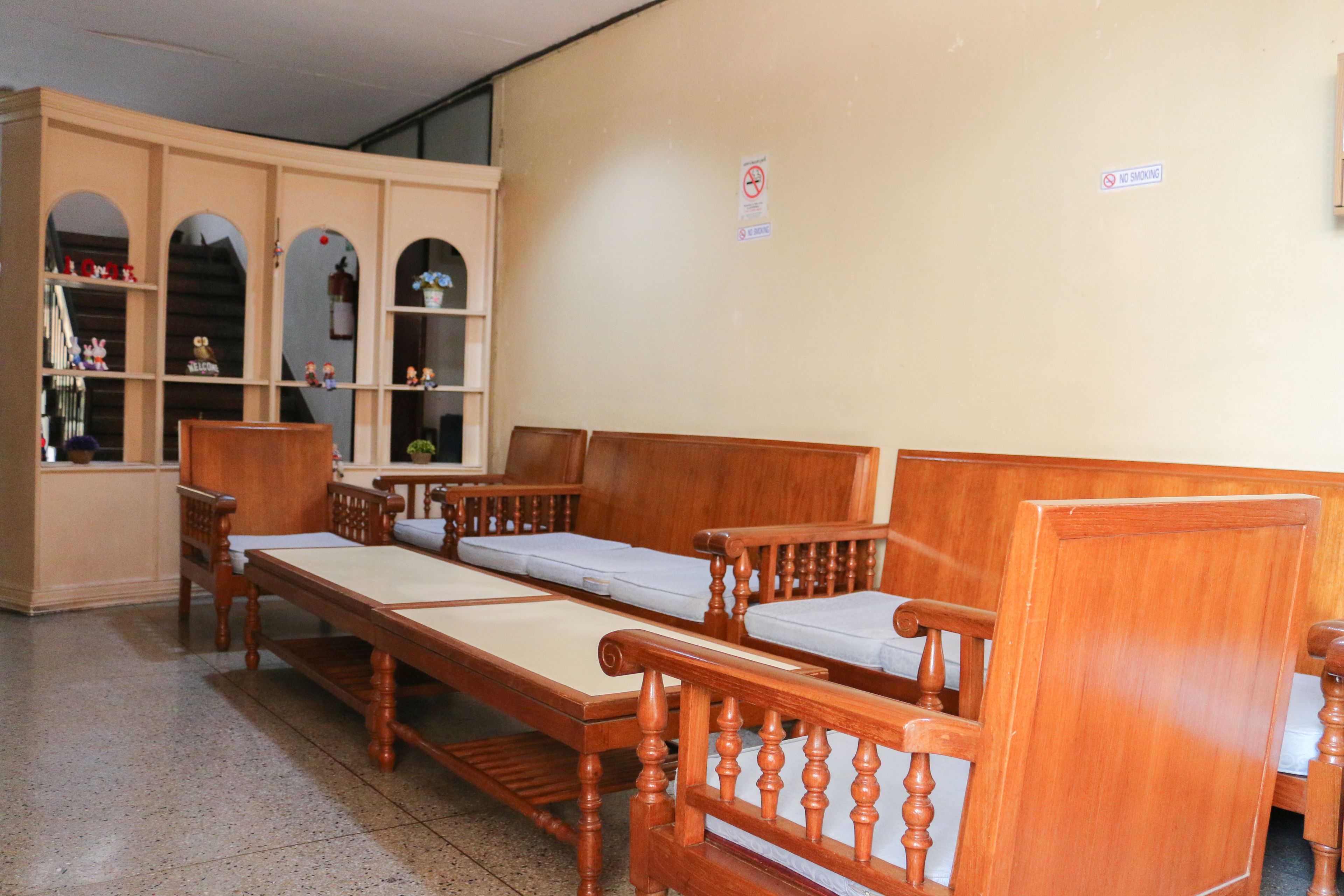 A room with wooden furniture including a sofa and a bed with a wooden headboard. There are shelves with various items on them.