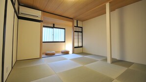 Ein traditioneller japanischer Raum mit Tatami-Boden, einer Schiebetür und einem Deckenventilator.