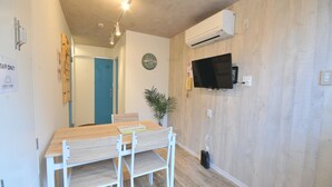Une cuisine moderne avec une table et des chaises en bois, une horloge et un climatiseur fixé au mur.