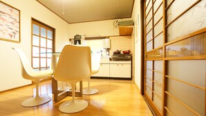 A compact kitchen with modern appliances, a dining area with two white chairs, and a traditional sliding door.