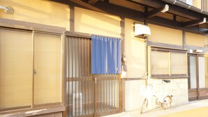 A building with closed shuttered windows, a bicycle parked outside, and a blue curtain on one of the doors.