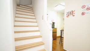 Un escalier mène à un espace cuisine équipé d’un réfrigérateur, d’un four à micro-ondes et d’une machine à café.