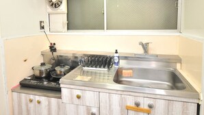 Une cuisine avec des meubles de rangement en bois, une cuisinière, un évier et une fenêtre au-dessus de l’évier.