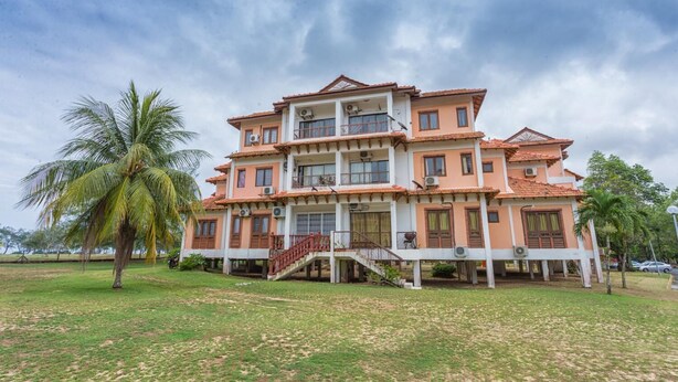 A multi-story building with a balcony, a staircase, and a palm tree in the foreground.