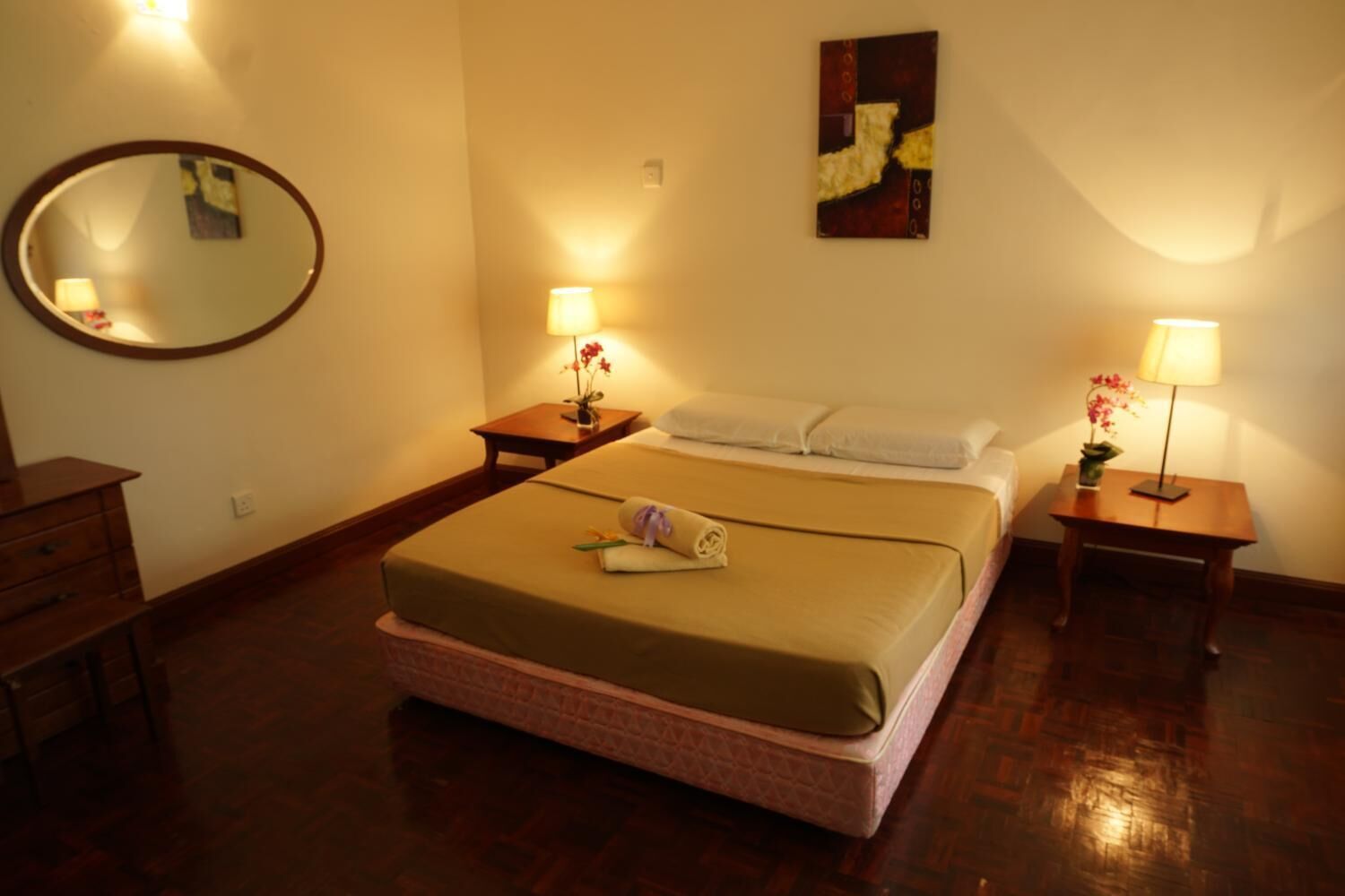 A hotel room with a bed, two bedside tables, a mirror, and a painting on the wall.