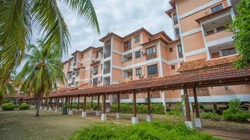 A multi-story hotel with balconies, a covered walkway, and palm trees.