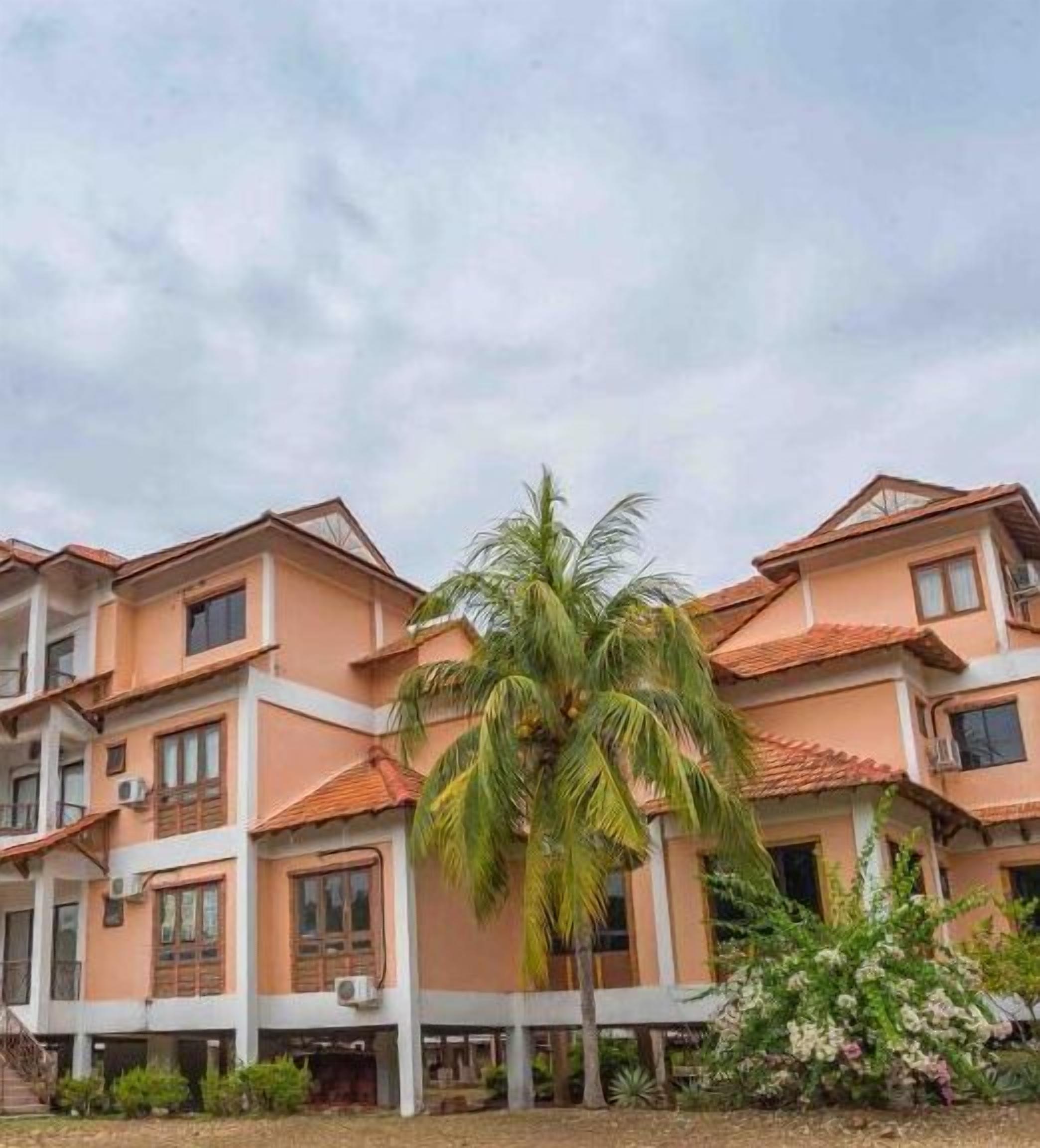 A multi-story building with a consistent architectural style, featuring balconies and a central courtyard with a palm tree.