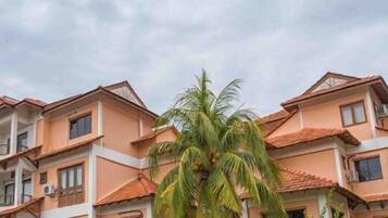 A multi-story building with a consistent architectural style, featuring balconies and a central courtyard with a palm tree.