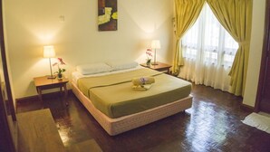 A hotel room with a large bed, two bedside tables with lamps, a wall-mounted artwork, and a window with curtains.