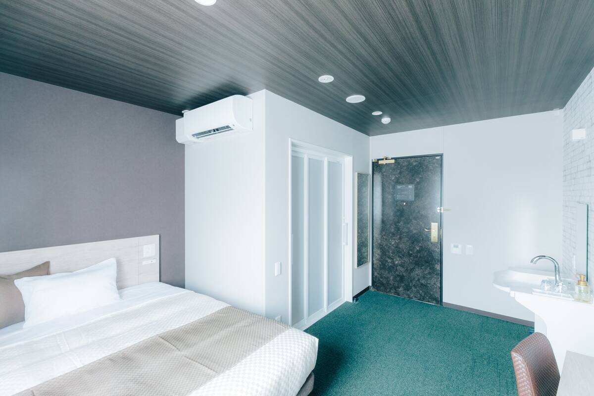 A modern hotel room with a large bed, a bathroom with a glass shower, and a small seating area.