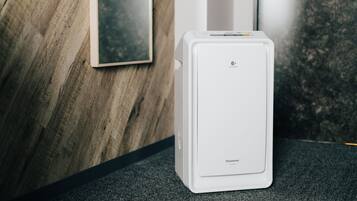 Un réfrigérateur Panasonic blanc se trouve dans une pièce dont un mur est en bois et où est accroché un tableau encadré.