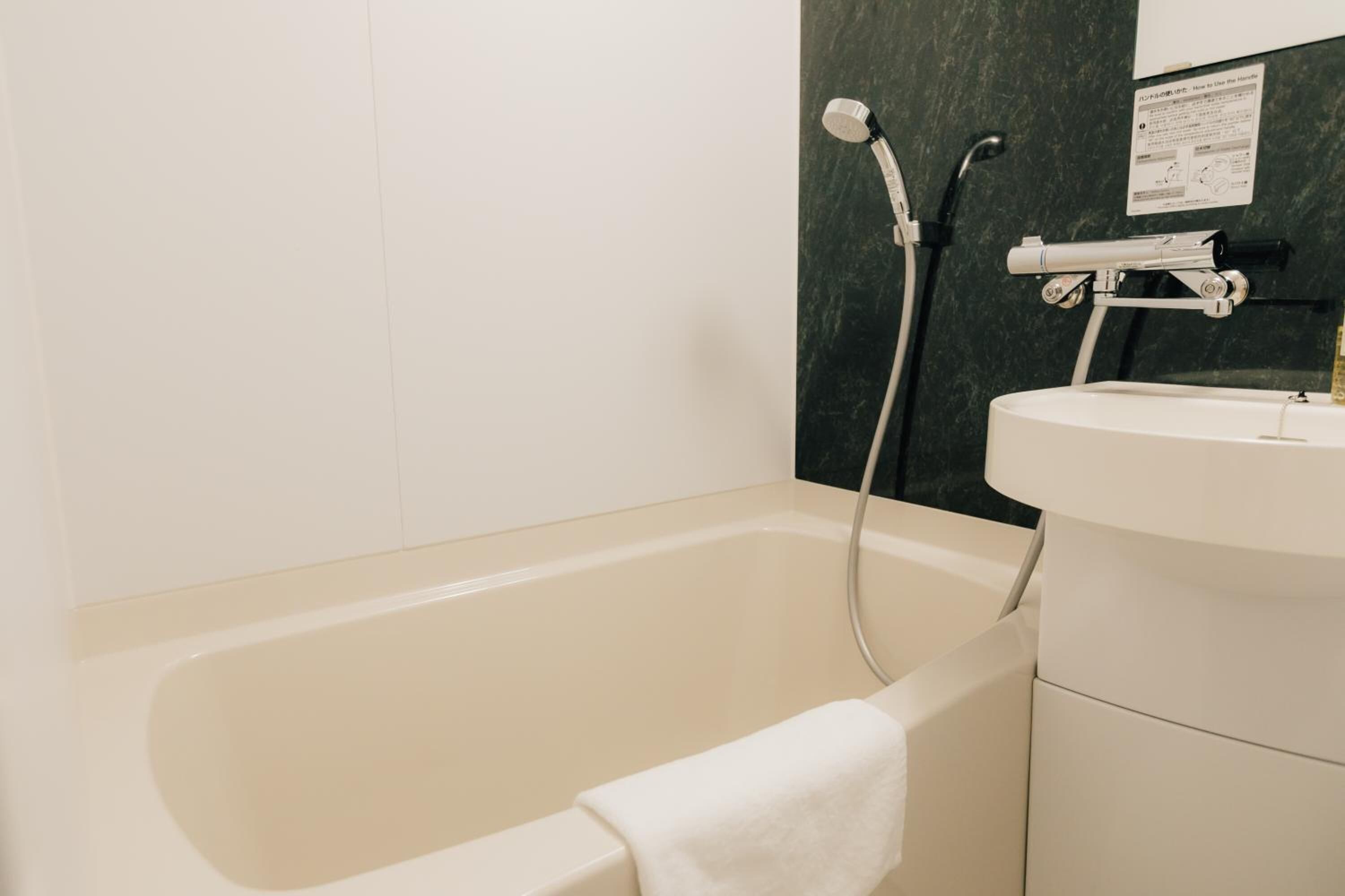 A bathroom with a bathtub, a sink, and a shower head.
