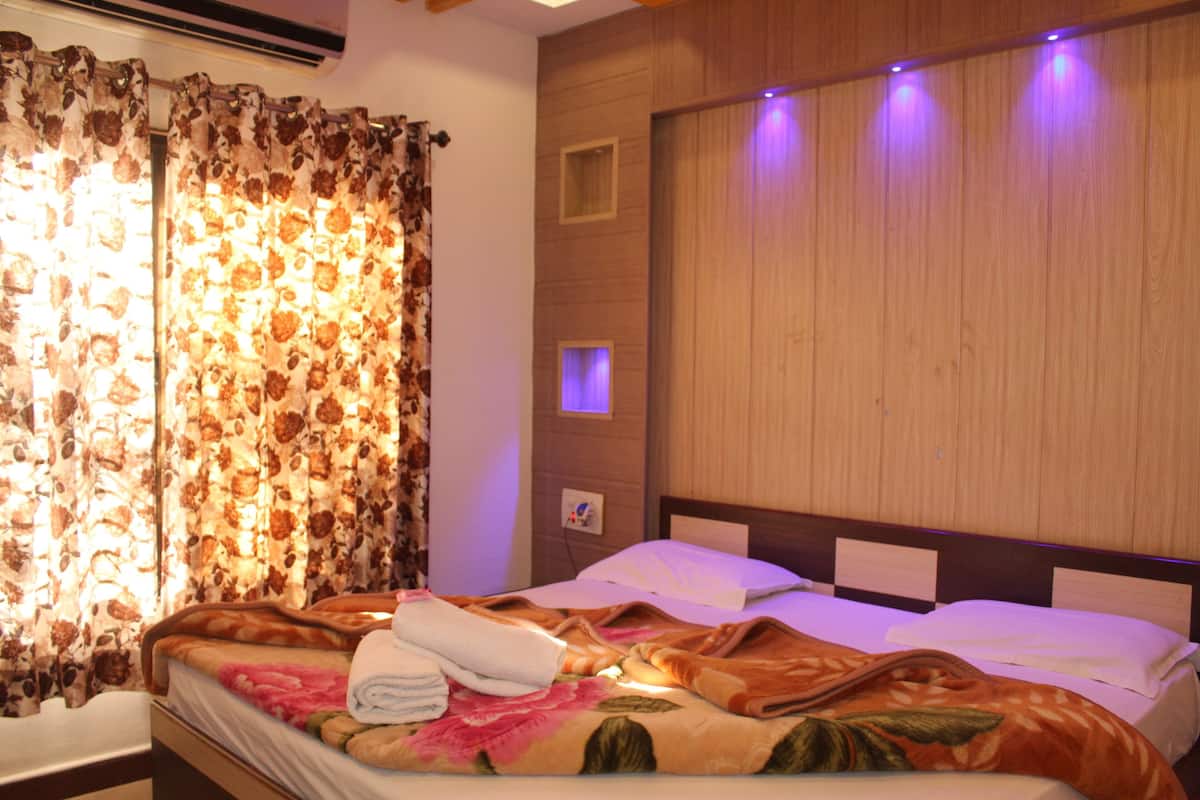 Une chambre d’hôtel avec un lit, des rideaux, une lampe fixée au mur et un petit cadre photo.