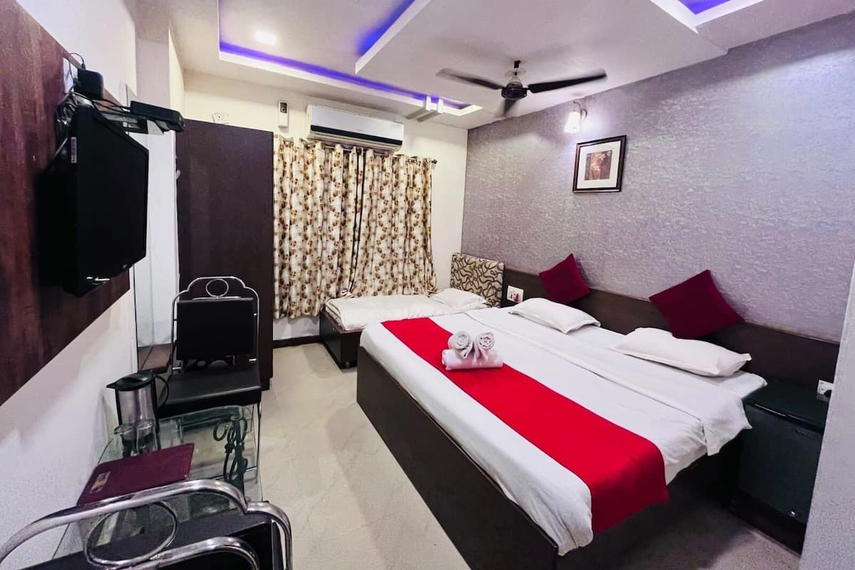 Une chambre d’hôtel équipée d’un lit, d’un bureau, d’une chaise, d’une télévision et d’un ventilateur de plafond.