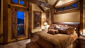 Un dormitorio con una cama grande, vigas de madera, un balcón y vistas a la ciudad.