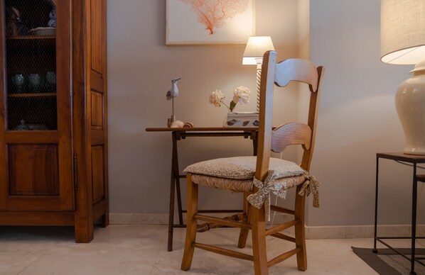 A wooden chair with a cushion, a small table with a lamp, and a decorative item on the table.