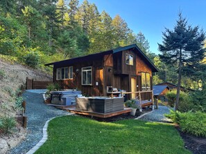 Eine rustikale Holzhütte mit einer Terrasse, Sitzgelegenheiten im Freien und einem Whirlpool.