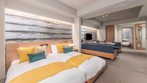 Una habitación de hotel moderna con una cama grande, un sofá, un televisor y vista al océano.