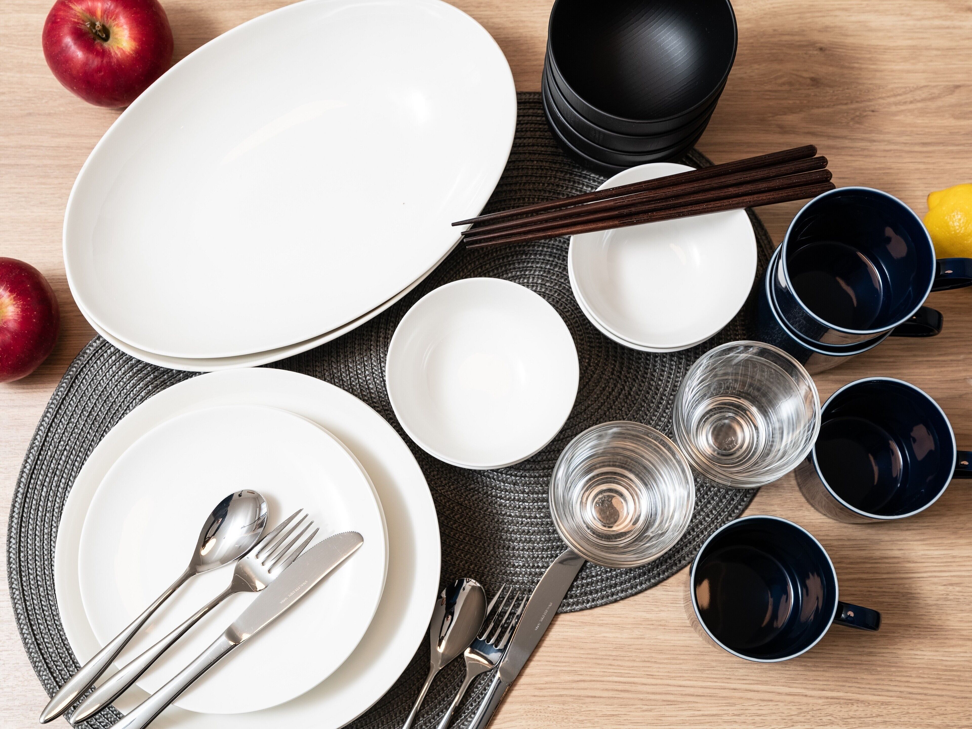Una mesa de comedor ordenada con platos, tazones, palillos y cubiertos.