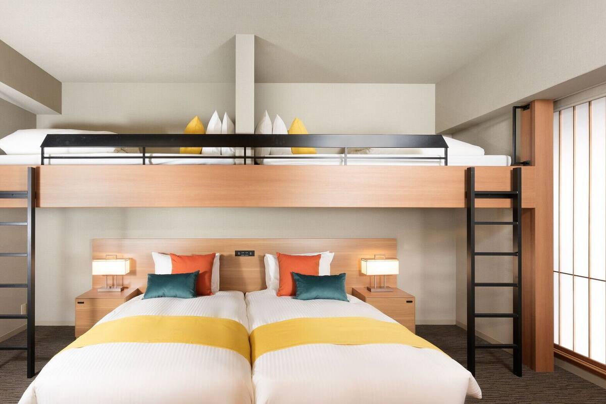 Une chambre avec un lit superposé, un bureau, deux tables de chevet, une tête de lit et une fenêtre.