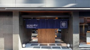 De ingang van Mimaru Apartment Hotel, met een donkerblauwe banner waarop de naam en locatie van het hotel staan.