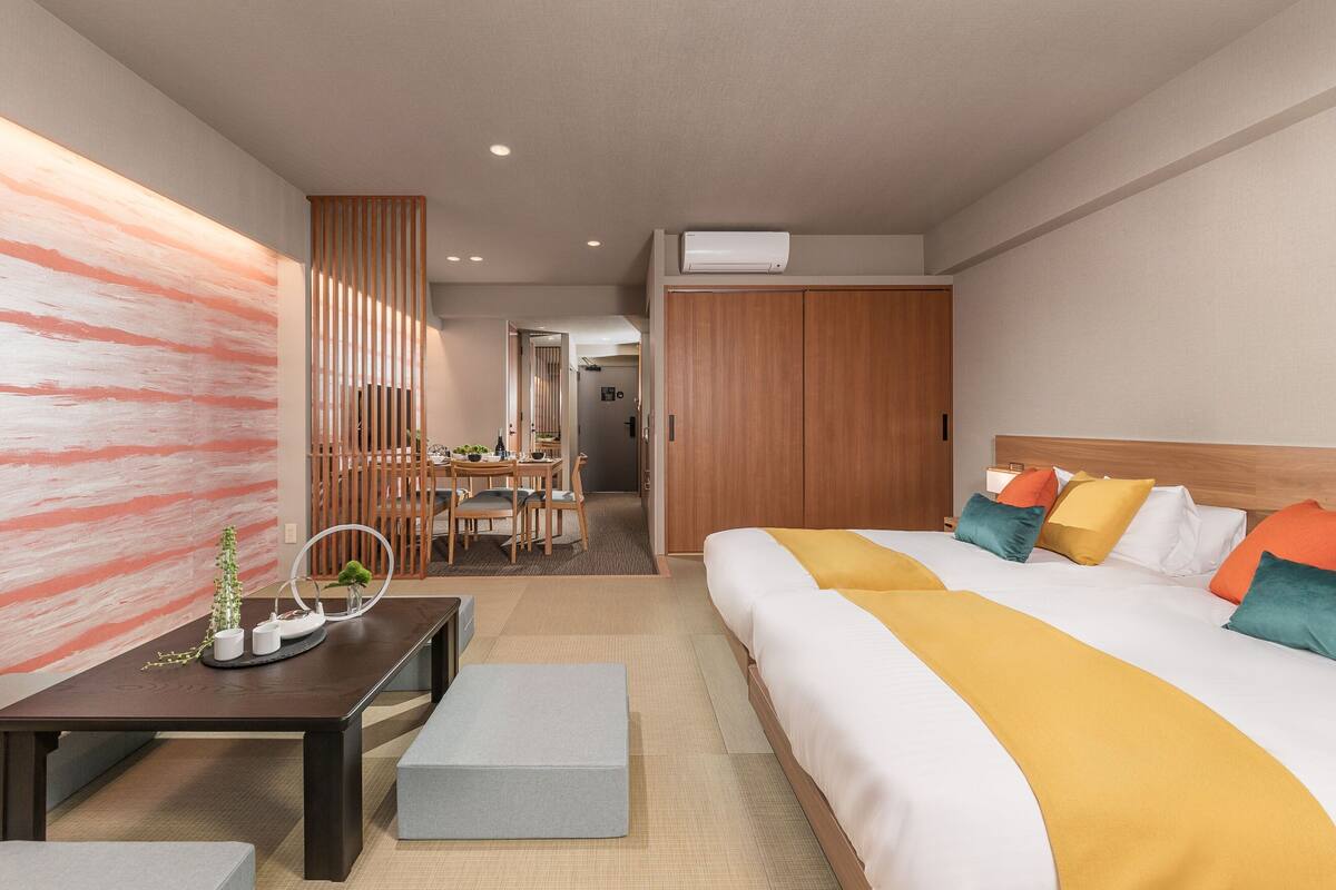 Une chambre d’hôtel moderne avec un grand lit, une armoire en bois, un coin repas et un mur décoratif.