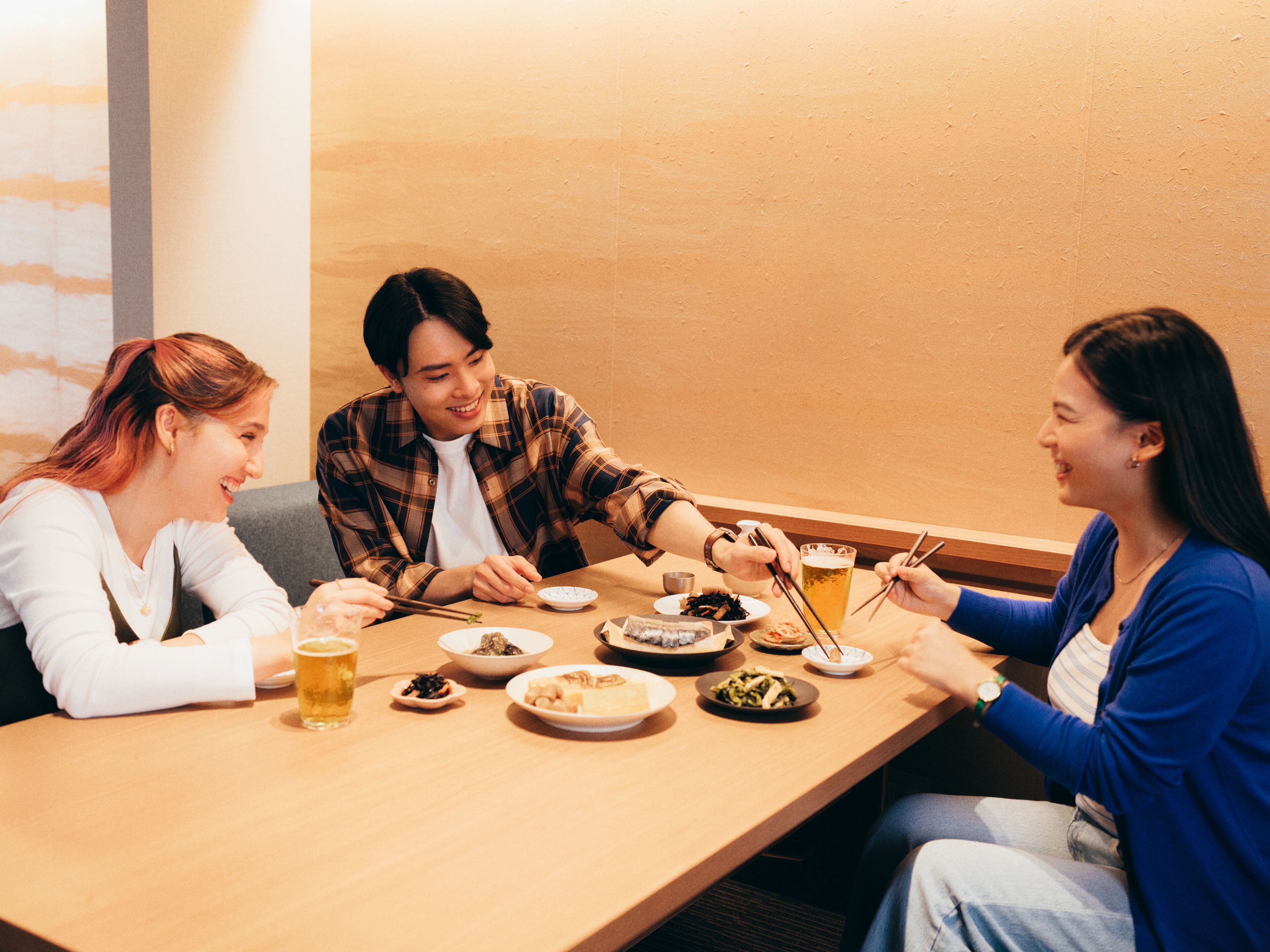 A group of people dining at a table with various dishes and drinks.
