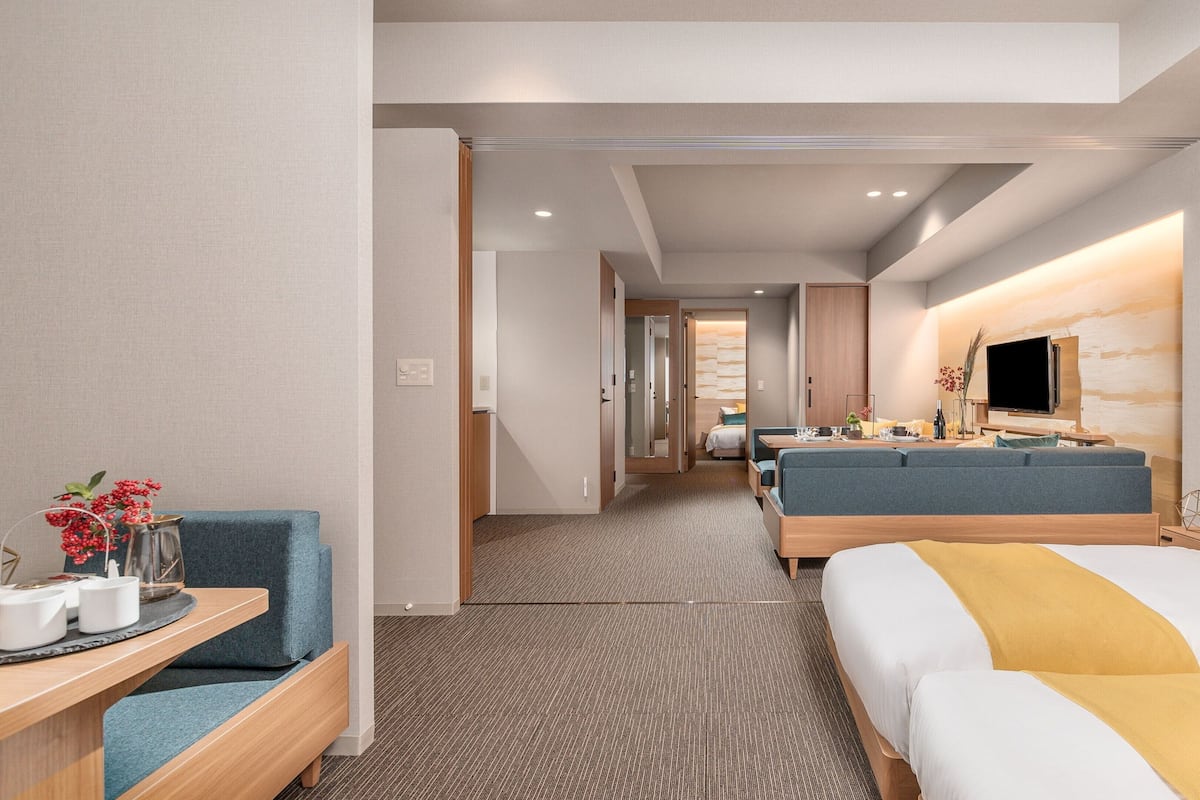 A hotel room with a bed, a sofa, a desk, and a television.