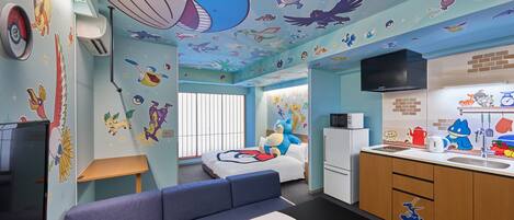 A room with a bed, a sofa, a kitchen area, and a ceiling with cartoon character decals.