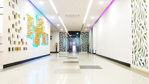 A modern hotel corridor with a reflective floor, decorative wall panels, and a central light fixture. - Hotel Khan Palace (Kalapara)