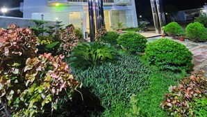 A hotel with a modern facade, a central entrance with a glass canopy, and a well-maintained garden area. - Hotel Khan Palace (Kalapara)
