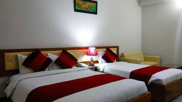 Una habitación de hotel con dos camas, una mesita de noche, una lámpara y un cuadro en la pared.