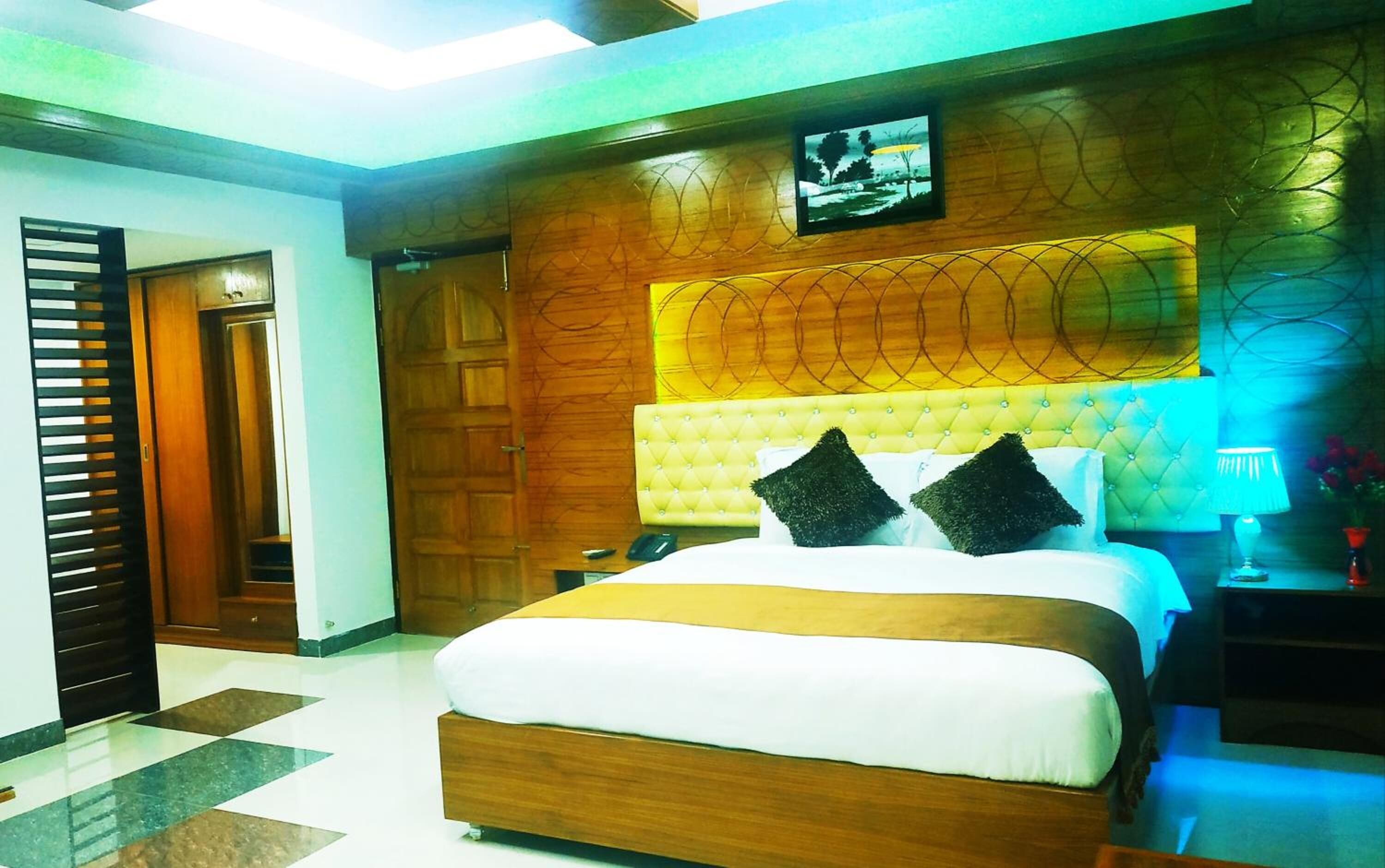 A hotel room with a large bed, wooden headboard, and a television mounted on the wall.