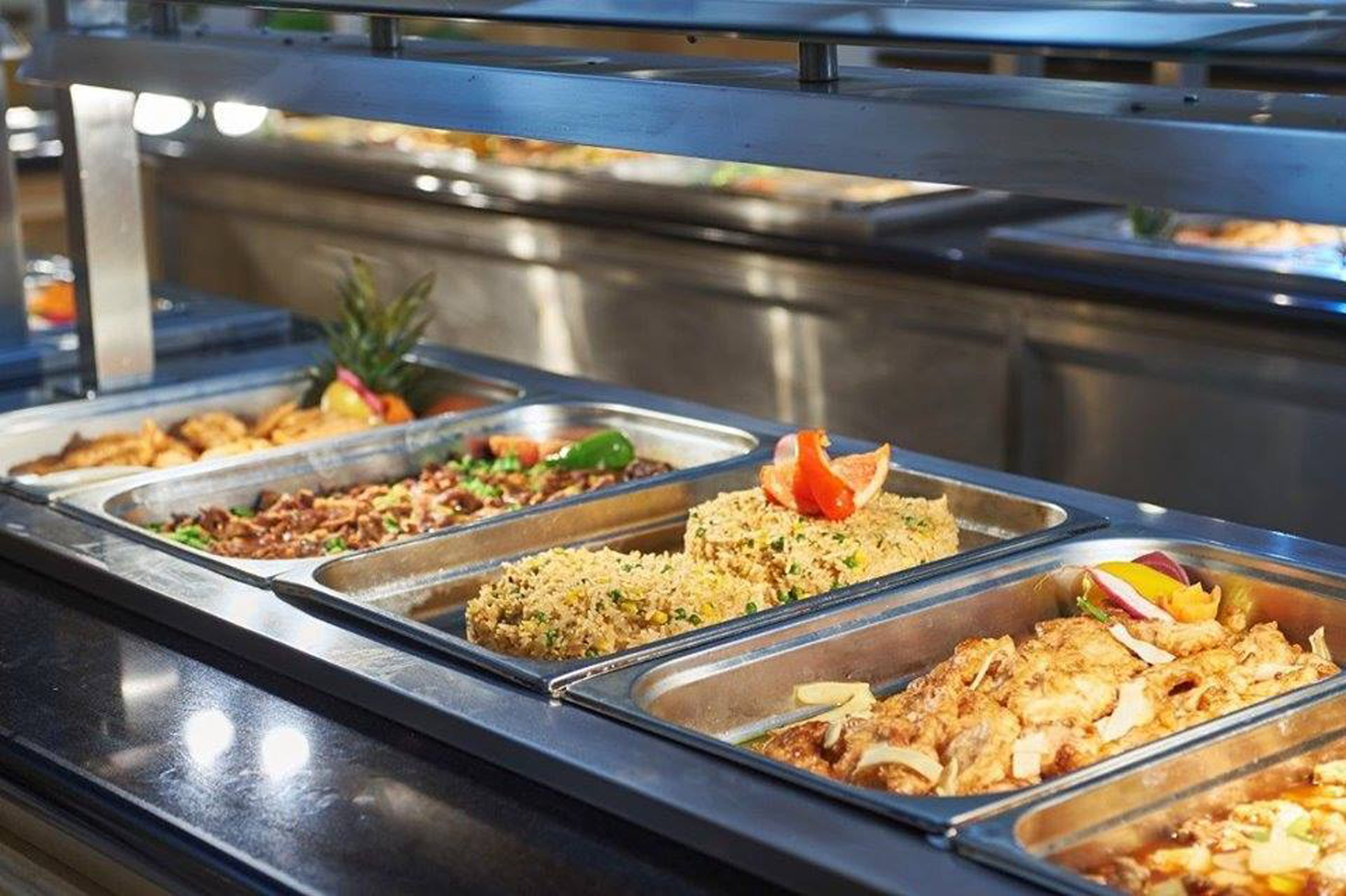 Buffet com diversos pratos, incluindo arroz frito, frango e saladas.