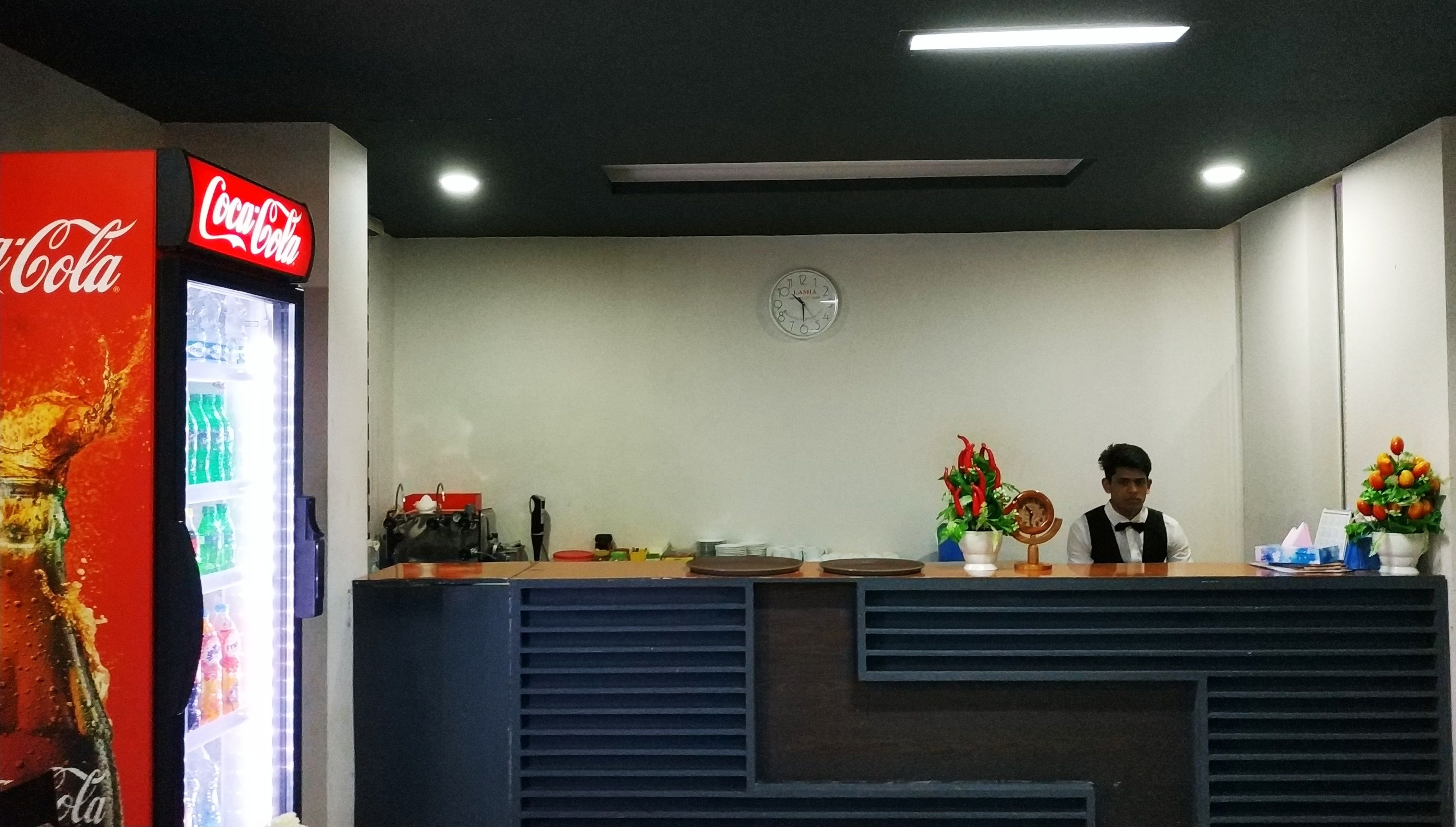 Una recepción con un refrigerador de Coca-Cola, un reloj y dos arreglos florales.