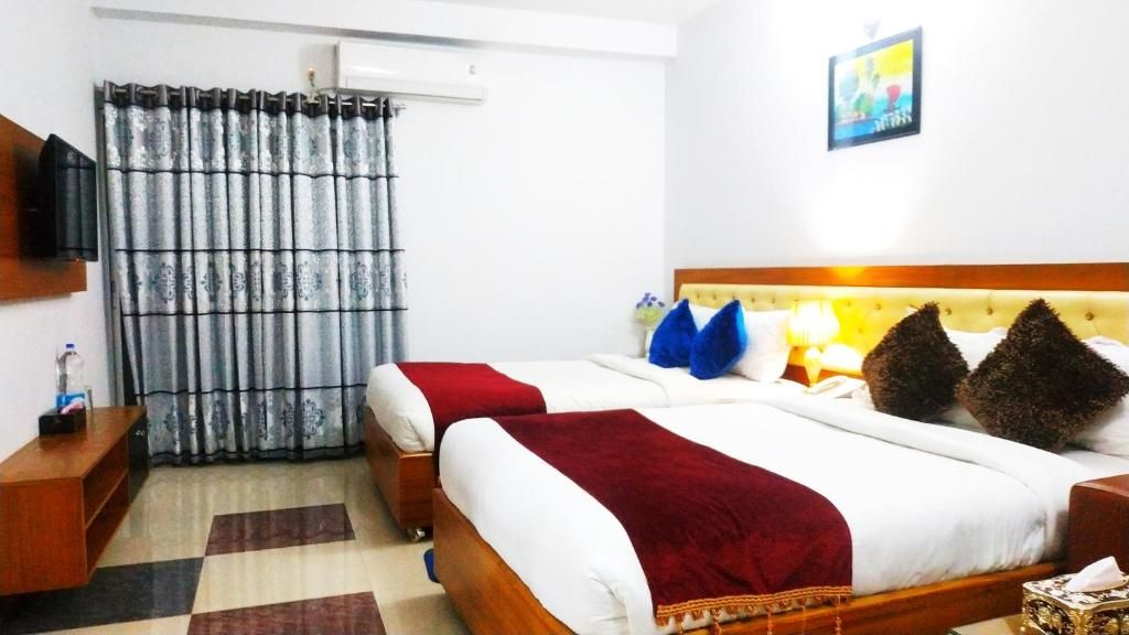 A hotel room with a bed, a television, a curtain, and a painting on the wall.