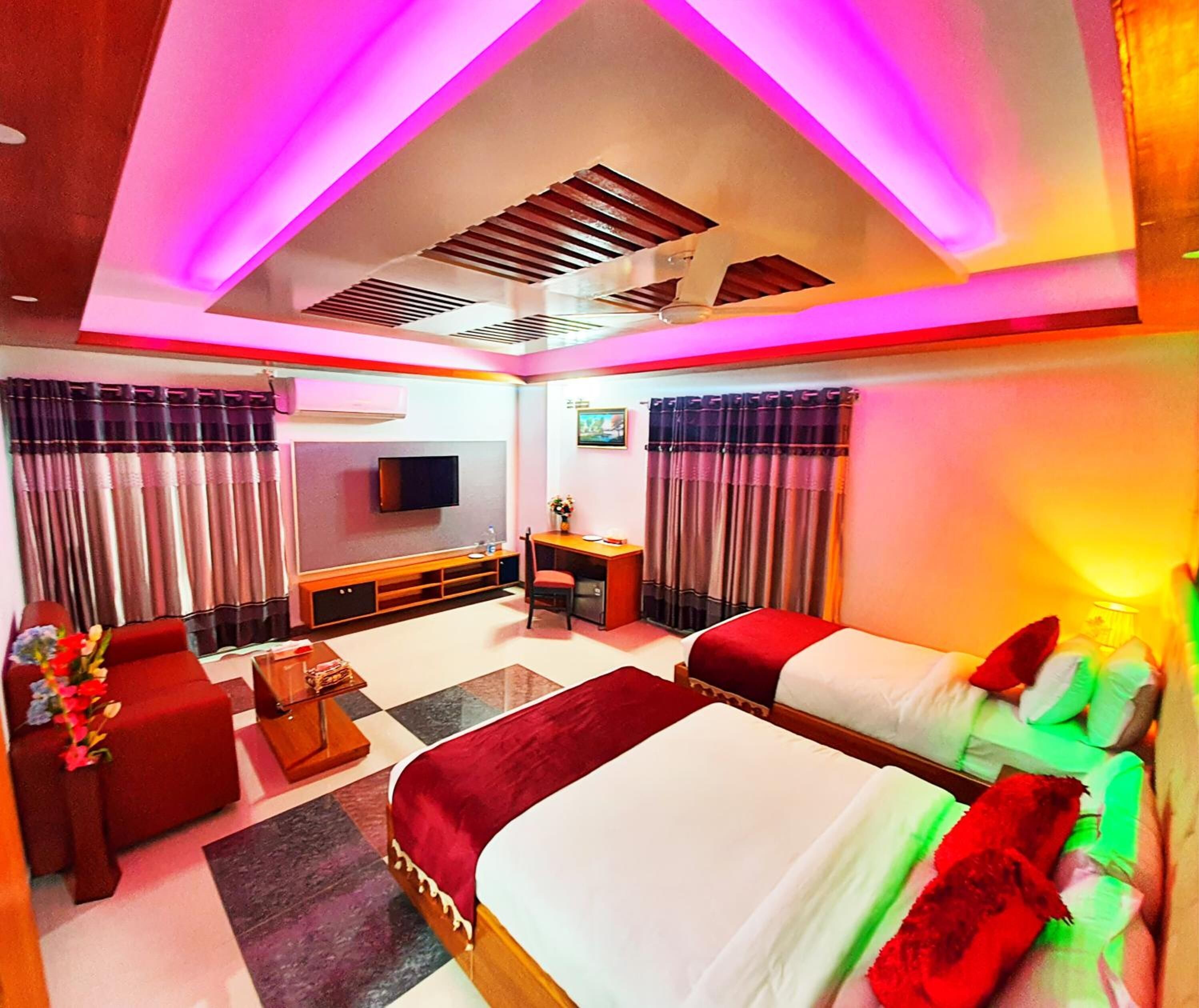 A modern hotel room with a large bed, a desk, a TV, and a sofa.