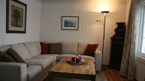 Uma sala de estar com um sofá, uma mesa de centro com velas, um abajur e um piano.