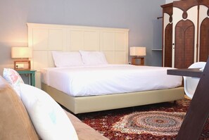 A bedroom with a large bed, two bedside tables with lamps, a wooden wardrobe, and a patterned carpet. - Rumah Kertajaya (Surabaya)