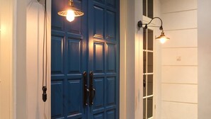 A blue door with two handles and a light fixture above it. - Rumah Kertajaya (Surabaya)
