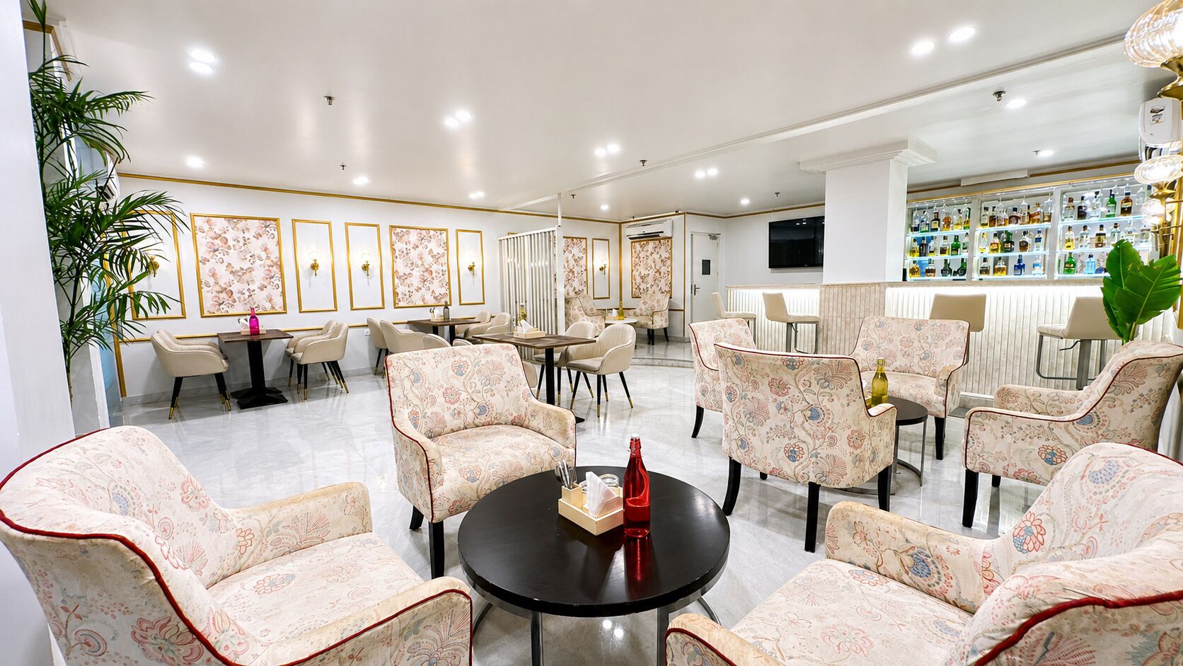 Ein geräumiger Lounge-Bereich mit gemusterten Sesseln, einem zentralen Tisch und einer Bar mit einer Auswahl an Flaschen.