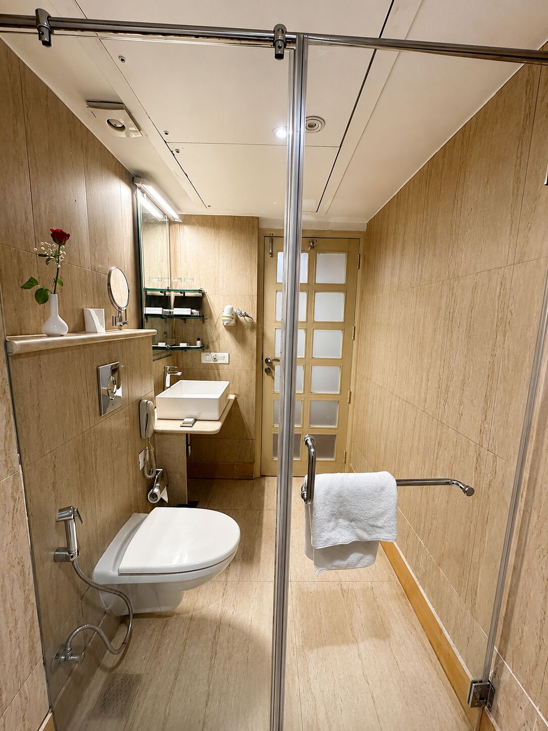 Ein modernes Badezimmer mit Glasdusche, Toilette, Waschbecken und einem Waschtisch mit Spiegel.