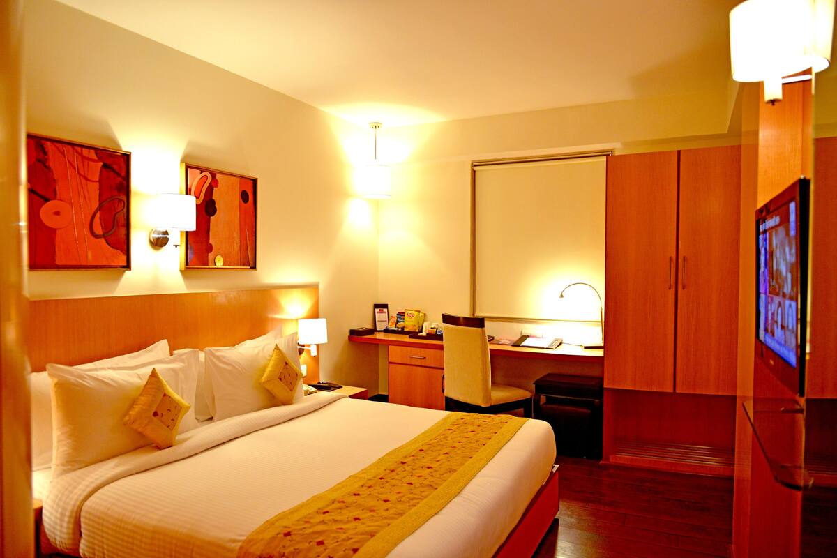 Une chambre d’hôtel avec un grand lit, un bureau, une chaise et un téléviseur.