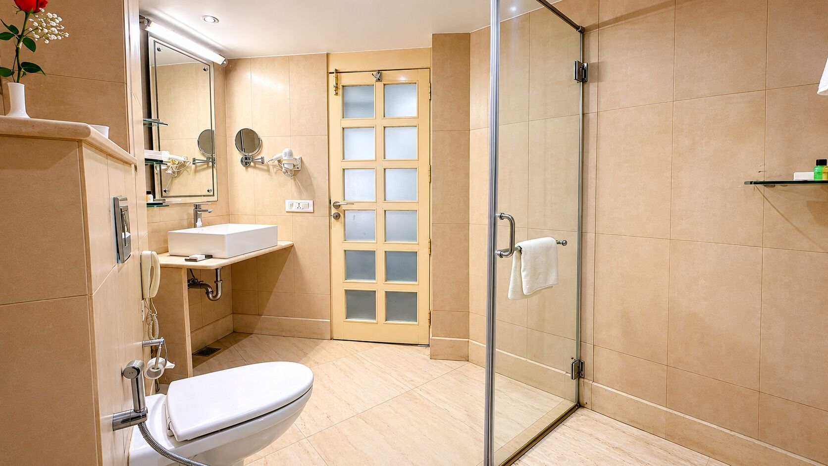 Ein modernes Badezimmer mit einer Duschkabine aus Glas, einer Toilette, einem Waschbecken mit Spiegel und einem Waschtisch.