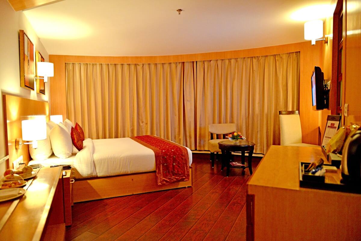Une chambre d’hôtel comprenant un lit, une table de chevet, une lampe et un bureau avec une chaise.