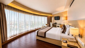 A hotel room with a large bed, a desk with a chair, a television, and a window with curtains. - The Theme Hotel Jaipur (Jaipur)